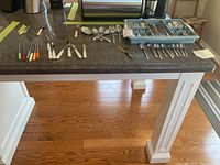 Wide view of different cutlery spread on countertop, including spoons, knives, forks, and fondue forks.