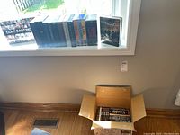 Boxes and shelf displaying DVDs and VHS tapes including Clint Eastwood collection and other titles