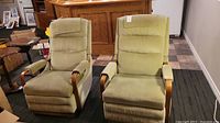 Front view of two matching vintage La-Z-Boy recliners with greenish fabric upholstery and wood arms, showing condition and style.