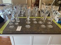 Wide angle photo showing all crystal glasses arranged on a table including wine glasses, champagne flutes, and liqueur glasses.