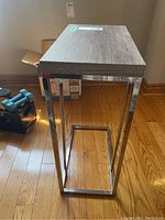 Side table showing the top surface and metal base from a front angle on a wood floor.