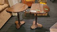 Pair of wooden side tables with double-sided drop leaves, visible wear, placed indoors on carpet