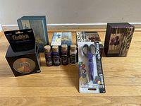 Photo shows all items in lot: four decorative storage boxes, five bottles of acrylic paint, one pack of Fiskars craft scissors, and one chalk kit box.