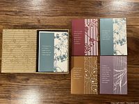 Photo of the blank cards with various botanical and abstract printed designs and quotes, and the storage box with a textured pattern.