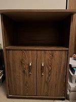Front view of wood grain cabinet showing two doors and top open shelf