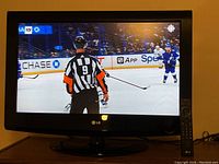 LG 37-inch flat screen TV displaying a hockey game on screen. Remote control is visible to the side of the TV.