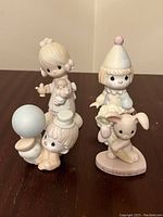 Four Precious Moments figurines shown together on a flat surface with neutral background