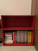 Red wooden bookshelf with two shelves, showing size and condition.