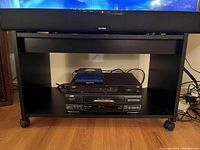 TV stand on wheels with Bell TV box and JVC VHS player placed on middle shelf.