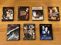 Photo of seven assorted DVDs on a wooden surface.