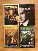 Four DVDs: Speed Collector Pack, Michael Douglas Collection, Dune Special Edition, and Hulk 2-Disc Special Edition arranged on wooden surface.