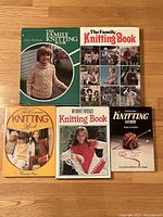 Five vintage knitting books arranged on a wood floor, showing front covers with images of knitwear and knitters.