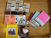 Top-down photo showing various packs of card stock, art papers, and unopened greeting card kits arranged in a grid