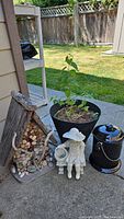 Full lot view showing birdhouse, potted tree, garden figurine, compost pail