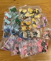 Photo showing various plastic bags filled with multiple embroidery thread skeins in assorted colors arranged on a wooden surface.