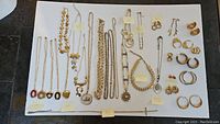 Lot overview photo showing 13 necklaces with various pendants including lockets, chains and earrings arranged on white background with brand tags visible