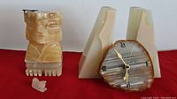 Two triangular onyx bookends with chips, clock with Roman numeral face, and small onyx figurine resembling a Sphinx or lion