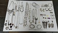 Full layout of silver-tone costume jewelry including necklaces, bracelets, earrings, and bangles on white background