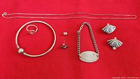 Set of sterling silver jewelry on a red fabric background showing all items including necklace, bracelet, ring, and earrings.