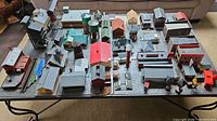 Top-down view showing a large layout of assorted HO scale train buildings and structures arranged on a board.