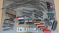Complete view of all train tracks, multiple locomotives and accessories laid out on a flat surface.