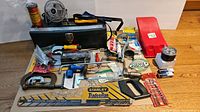 Overview photo of the Viking metal toolbox with various hand tools, Stanley Tradesman saw, mini electric fan, clamp, and other tools laid out on a wooden surface.