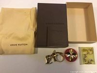 Overview of Louis Vuitton keychain, box, and dust bag, with three pairs of earrings in original box.