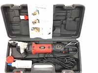 Photo showing electric sheep shearing clippers in red and black with electric cord, placed in molded hard plastic case. Includes clipper oil bottle and red accessory.