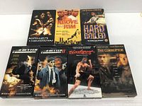 Photo showing all seven VHS tape boxes with titles Naked Weapon, Above the Rim, Hard Boiled, A Better Tomorrow I & II, Bloodsport, and The Corruptor