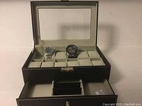 Watch box open showing two watches inside and storage drawer below