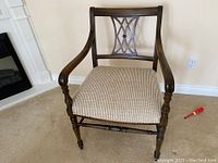 Front view of the vintage wooden armchair showing wooden arms and beige fabric seat.