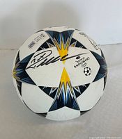 Full front view of the signed ball showing signature, star panel design, and Champions League logo