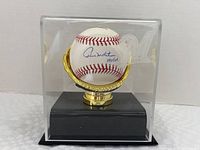 Front view of the signed baseball in the display case with Milwaukee Brewers logo visible on the case