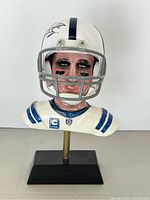 Full front view of painted resin bust with attached mini helmet showing helmet stripe, facemask and jersey details