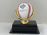 Signed baseball held in gold-tone glove display on black base