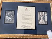 Overall gilt frame with navy mat showing letter at center flanked by two photographs