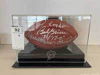 Front view of signed football in acrylic display case showing all autographs and Dolphins logo base