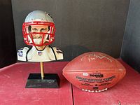 Resin bust with mini helmet on base displayed next to signed football