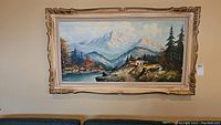 Framed original oil painting on canvas showing full view of mountainous landscape scene with river and cabin.