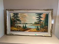 Full view of the framed landscape painting showing trees, lake, and distant shorelines.