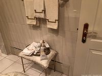 Photo of metal table with pillow on top, decorative tray with lotion bottle, angel figurine, candle, and towels hanging above