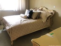 Full view of cream-painted bed frame with bedding and cushions.