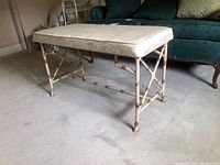 Front side view of rectangular bench with floral upholstery and bamboo-style metal base showing rust accents.