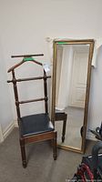 Image showing the vintage butler chair with turned spindle backrest and padded black seat alongside the floor mirror with decorative frame.