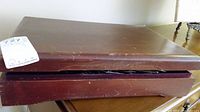 Closed view of the brown wooden cutlery box showing surface scratches and wear.