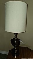 Full view of first table lamp with white cylindrical shade and dark metal base