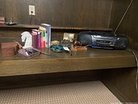 Wide view of the shelf showing multiple items including Sony radio and CD player, clock, pen holder, ashtray, napkin holder, horse figurine, bookend, and stapler.