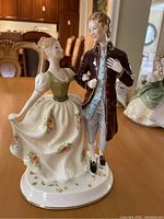 Full view of the Royal Doulton Young Love figurine showing the couple standing arm in arm in period clothing with floral accents on the woman's dress.