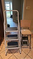 Front view of folding 3-step ladder and vintage 2-step stool side by side, showing their general size and structure.