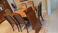 Dining table with six cane back chairs arranged around it, visible wood grain and cushioned chairs.